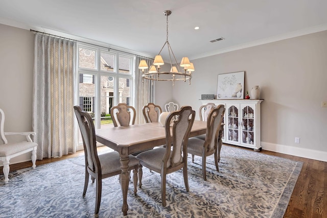 dining area featuring a chandelier, crown molding, visible vents, baseboards, and wood finished floors