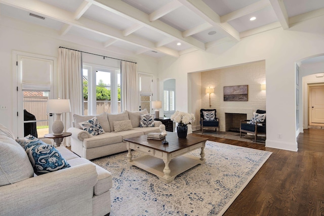 living area featuring dark wood-style floors, visible vents, arched walkways, and coffered ceiling