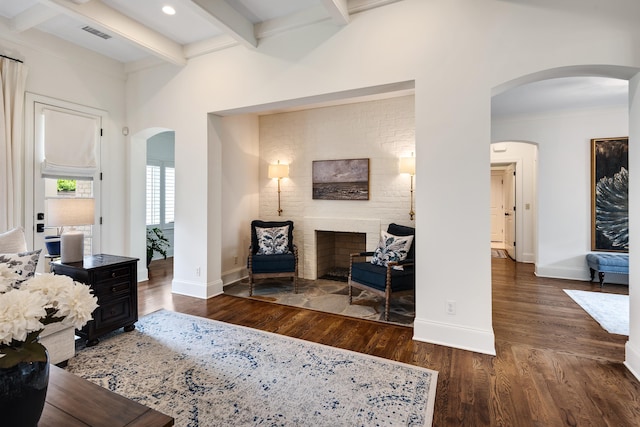 living area with beam ceiling, wood finished floors, and visible vents