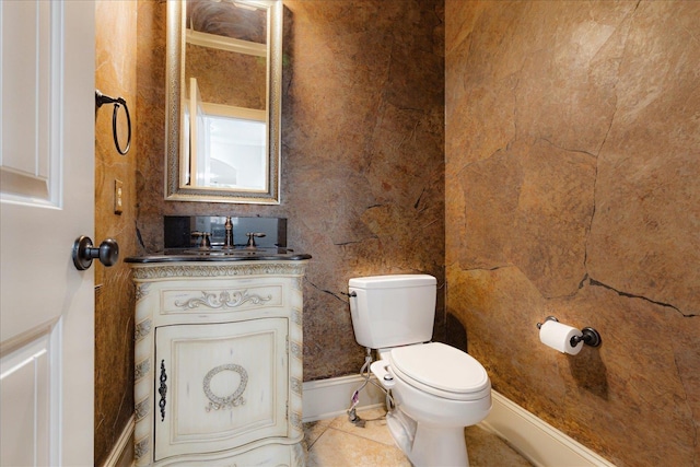 half bath with toilet, tile patterned floors, and vanity
