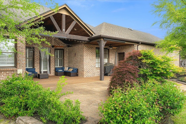 back of property featuring brick siding, a shingled roof, an outdoor hangout area, a patio area, and a ceiling fan