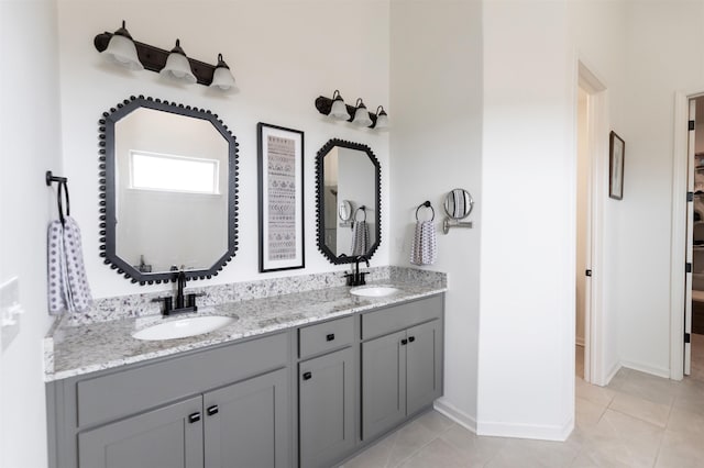 full bath with tile patterned floors, baseboards, double vanity, and a sink