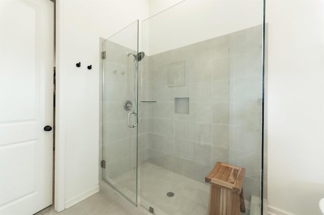 full bathroom with a shower stall, tile patterned floors, and baseboards