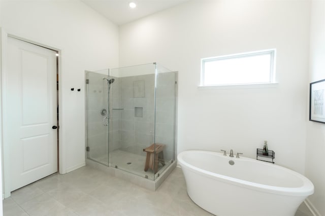 full bath featuring tile patterned floors, a freestanding bath, and a shower stall