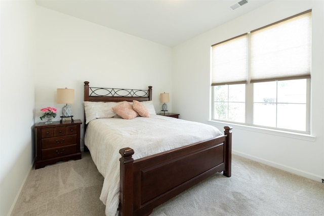 bedroom with visible vents, baseboards, and light carpet