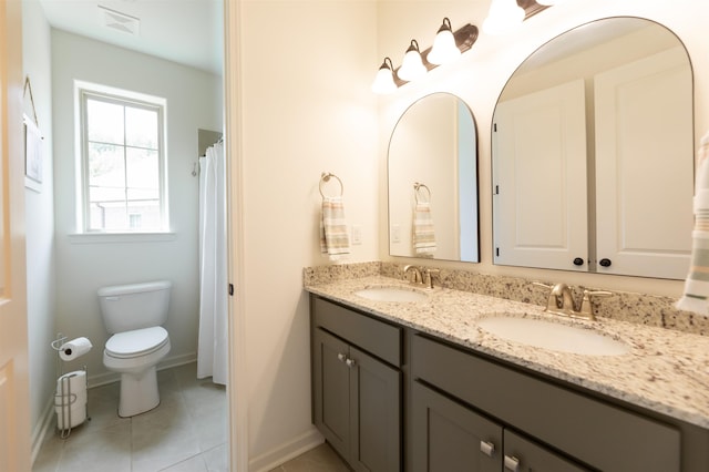 full bath featuring toilet, tile patterned flooring, double vanity, and a sink