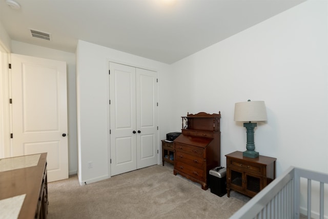 bedroom with a closet, visible vents, light carpet, and baseboards