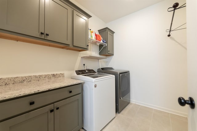 clothes washing area featuring light tile patterned flooring, cabinet space, independent washer and dryer, and baseboards
