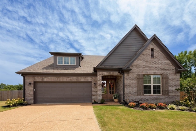 craftsman house featuring concrete driveway, a front yard, an attached garage, fence, and brick siding