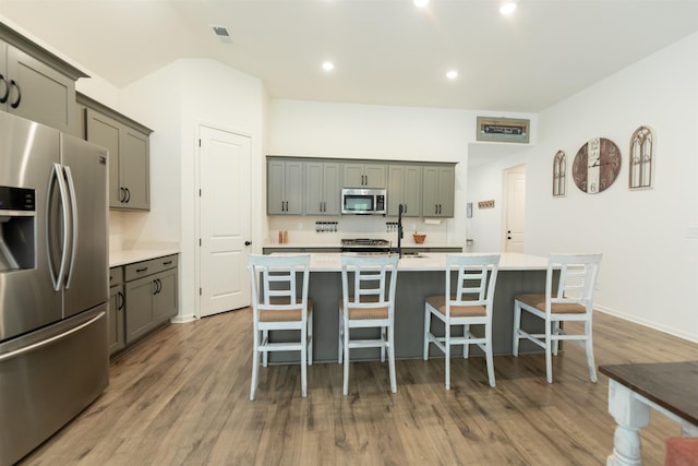 kitchen with a breakfast bar, stainless steel appliances, wood finished floors, and light countertops
