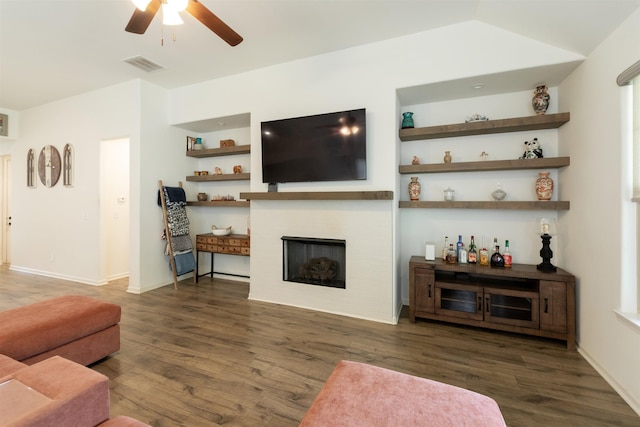 living area with wood finished floors, a fireplace, baseboards, visible vents, and a ceiling fan