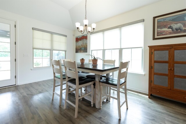 dining area featuring a notable chandelier, vaulted ceiling, wood finished floors, and baseboards