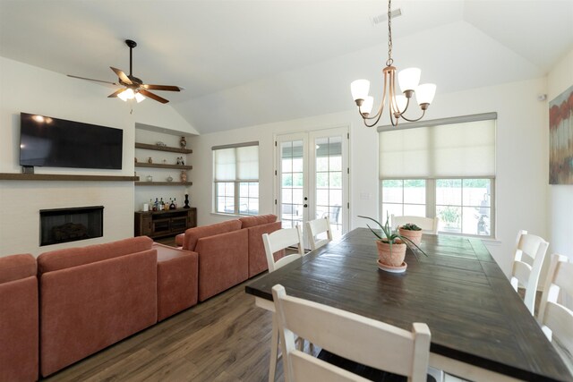 dining space with visible vents, vaulted ceiling, a fireplace, wood finished floors, and ceiling fan with notable chandelier