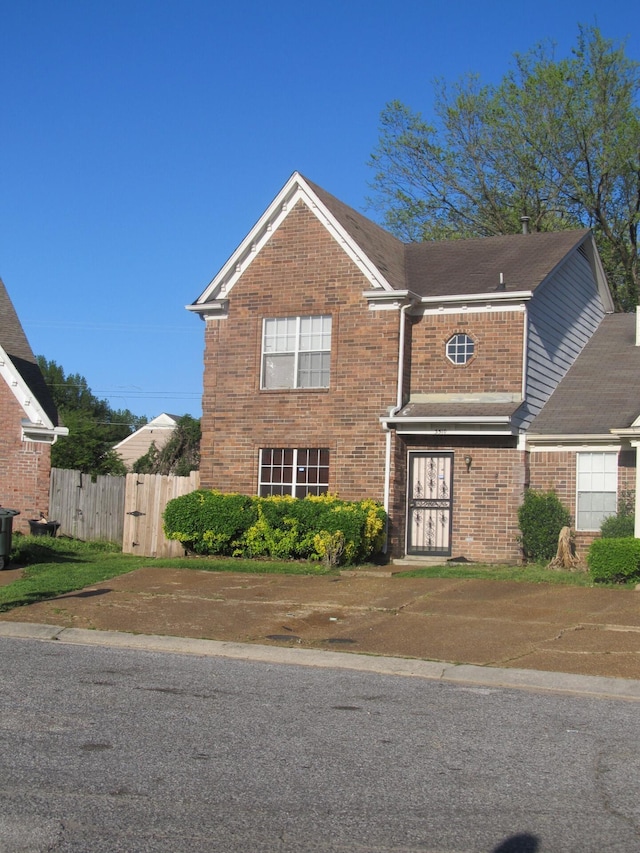 view of front of house featuring brick siding and fence
