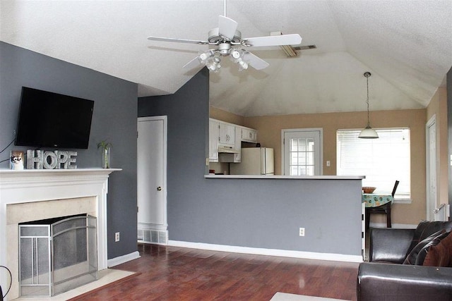 living area featuring dark wood finished floors, visible vents, ceiling fan, and vaulted ceiling
