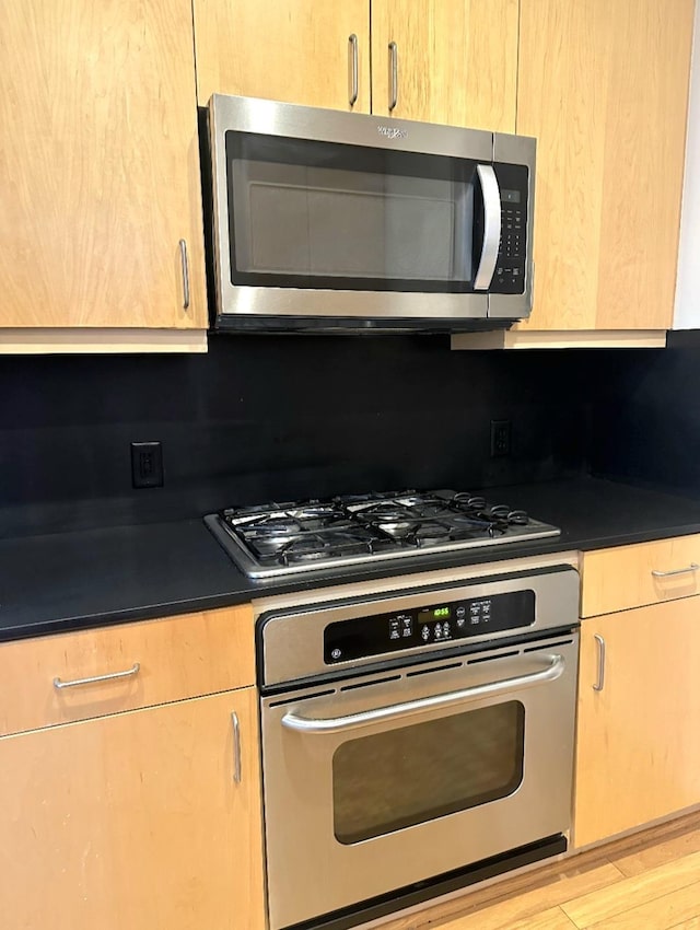 415 S Front St Unit 120, Memphis, TN 38103 - kitchen featuring stainless steel appliances, dark countertops, wood finished floors, and backsplash