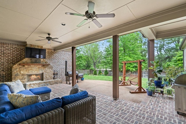 view of patio with grilling area, an outdoor living space with a fireplace, a ceiling fan, and a fenced backyard