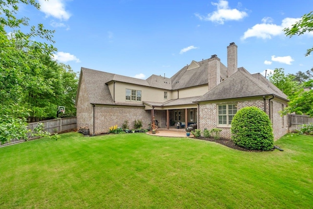 rear view of house featuring a patio, brick siding, fence private yard, a lawn, and roof with shingles