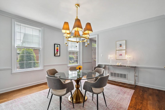 dining room featuring wood finished floors, ornamental molding, baseboards, visible vents, and a notable chandelier