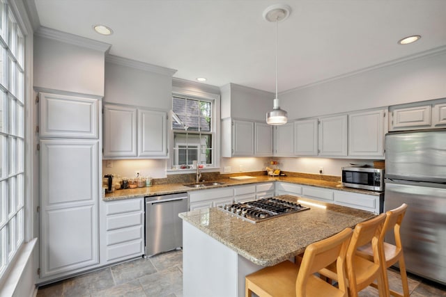 kitchen featuring a sink, a kitchen breakfast bar, light stone counters, ornamental molding, and appliances with stainless steel finishes
