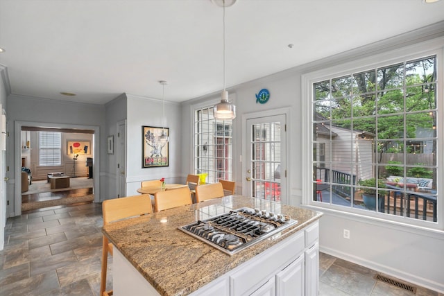 kitchen with ornamental molding, visible vents, stainless steel gas stovetop, and plenty of natural light