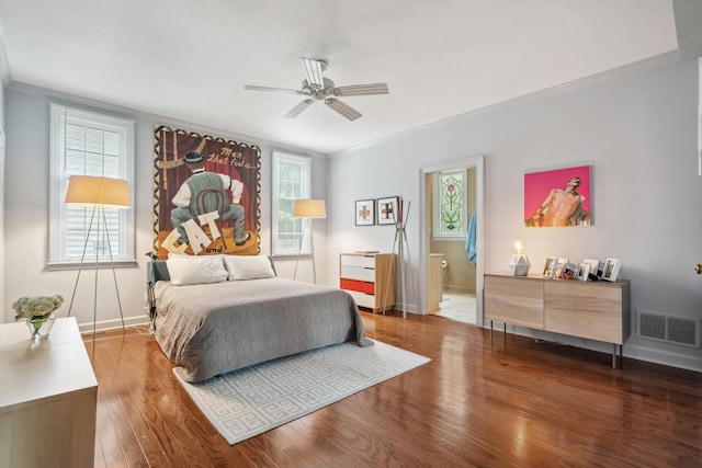 bedroom with wood finished floors, visible vents, ornamental molding, and multiple windows