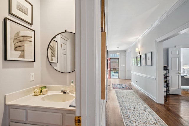 bathroom featuring ornamental molding, vanity, wood finished floors, and baseboards