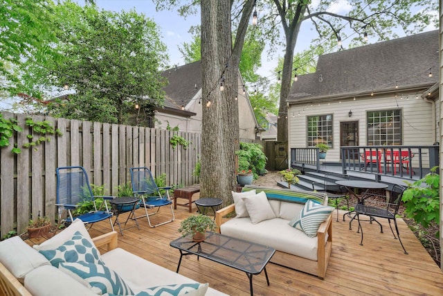 wooden terrace with an outdoor living space, outdoor dining area, and a fenced backyard