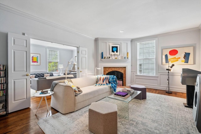 living room featuring wainscoting, wood finished floors, ornamental molding, and a fireplace