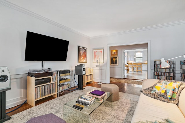 living room featuring ornamental molding, a wainscoted wall, and wood finished floors