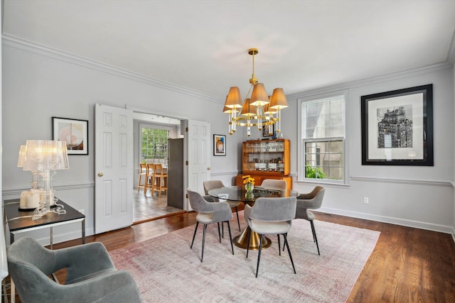 dining space with crown molding, an inviting chandelier, wood finished floors, and baseboards