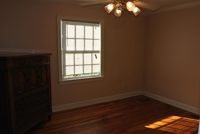 empty room featuring a ceiling fan, plenty of natural light, ornamental molding, and dark wood-style floors