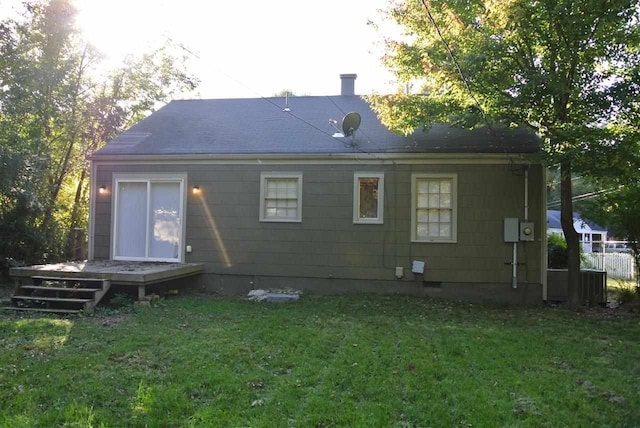 back of property featuring a lawn, a deck, and roof with shingles
