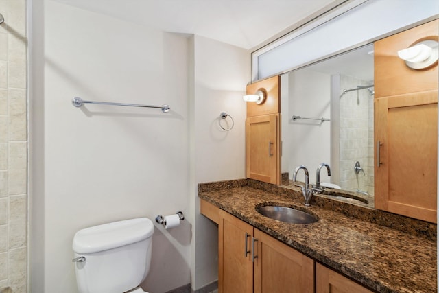 full bathroom featuring toilet, tiled shower, and vanity