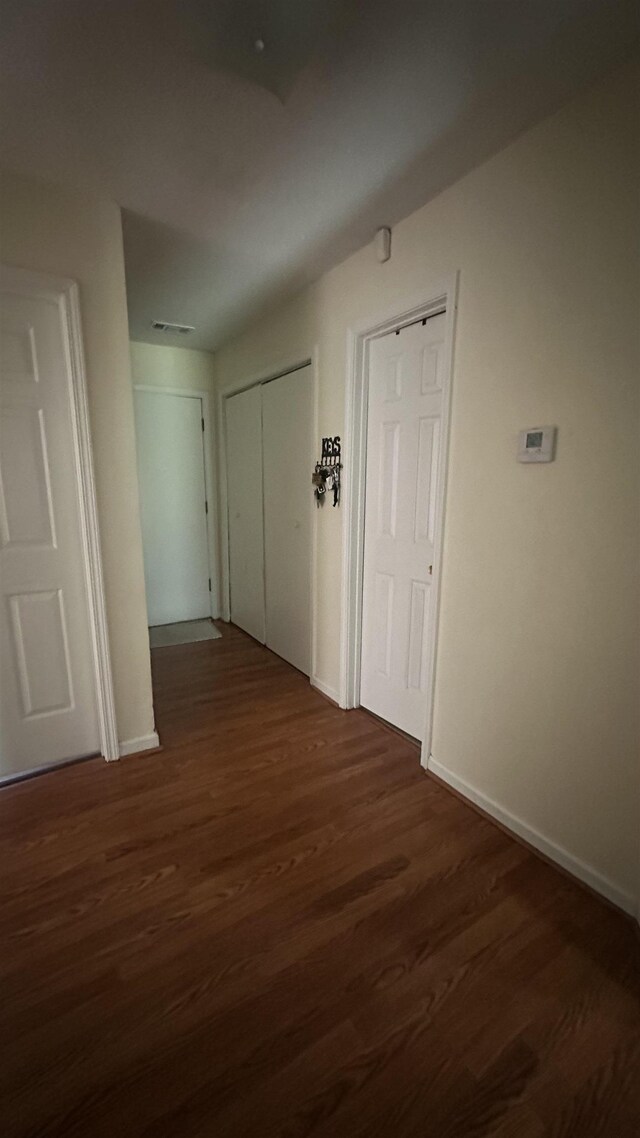 corridor featuring baseboards and wood finished floors