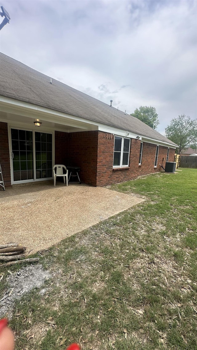 rear view of property featuring a yard, a patio, and brick siding