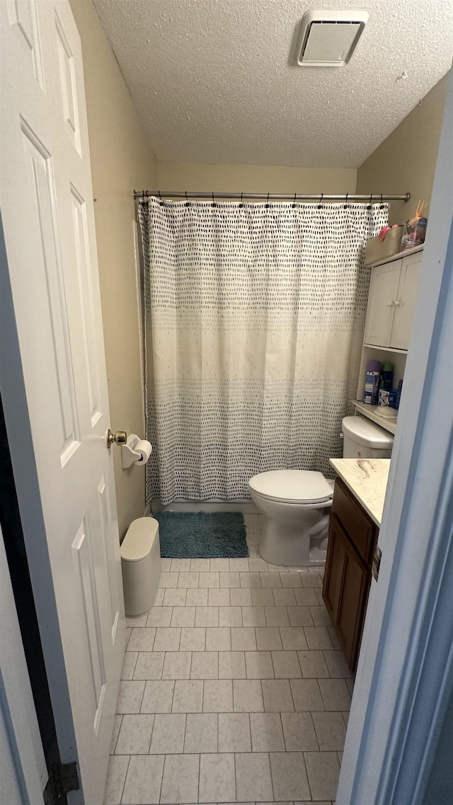 bathroom featuring toilet, vanity, a textured ceiling, and tile patterned floors