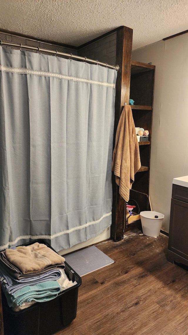full bathroom featuring wood finished floors, a shower with shower curtain, toilet, vanity, and a textured ceiling