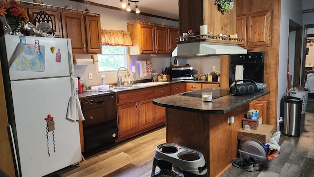 kitchen with black appliances, brown cabinets, light wood-type flooring, and a sink