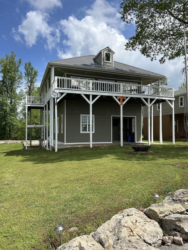 back of property with a yard, a wooden deck, and metal roof