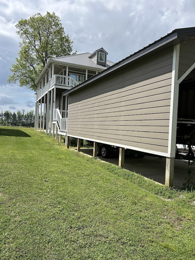 view of side of home featuring metal roof, a yard, and a balcony