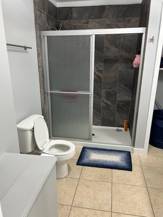 bathroom featuring toilet, a stall shower, and tile patterned flooring