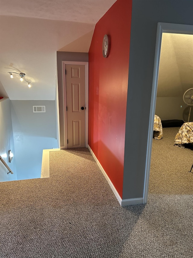 hall featuring an upstairs landing, visible vents, carpet floors, and baseboards