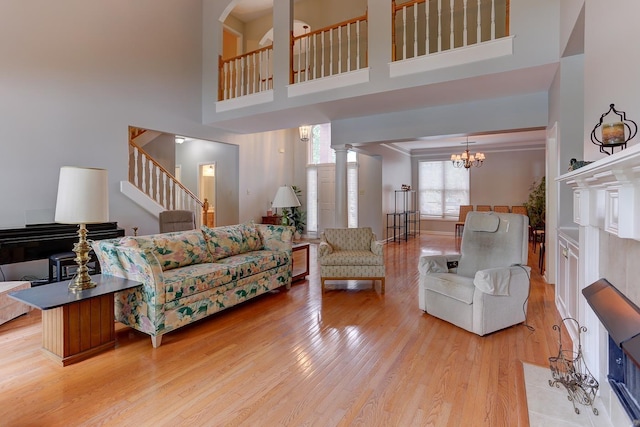 living area featuring an inviting chandelier, a towering ceiling, light wood-style flooring, and stairs