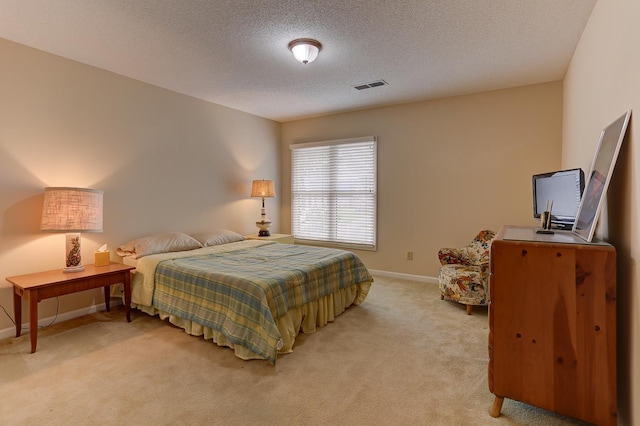 bedroom with light colored carpet, visible vents, baseboards, and a textured ceiling