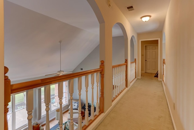 hall featuring lofted ceiling, light colored carpet, and visible vents