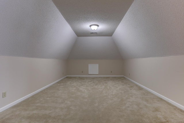 bonus room with a textured ceiling, carpet flooring, visible vents, baseboards, and vaulted ceiling