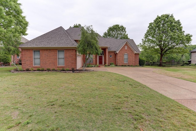 single story home featuring brick siding, fence, driveway, roof with shingles, and a front yard