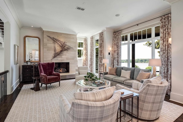 living room featuring wood finished floors, visible vents, crown molding, and baseboards