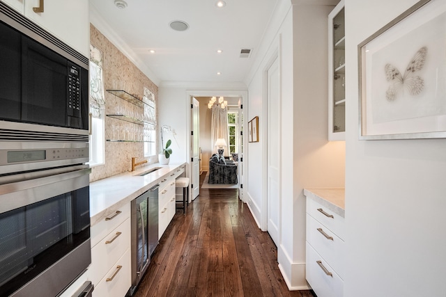 kitchen featuring white cabinetry, a chandelier, built in microwave, oven, and wine cooler